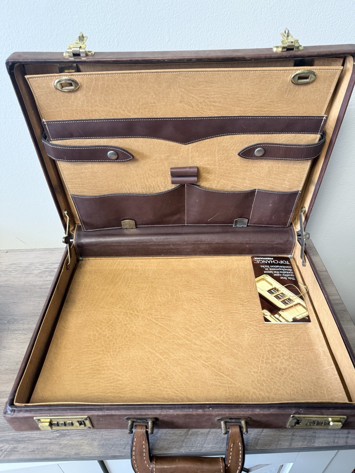 A vintage brown leather briefcase with combination lock and metal hardware.