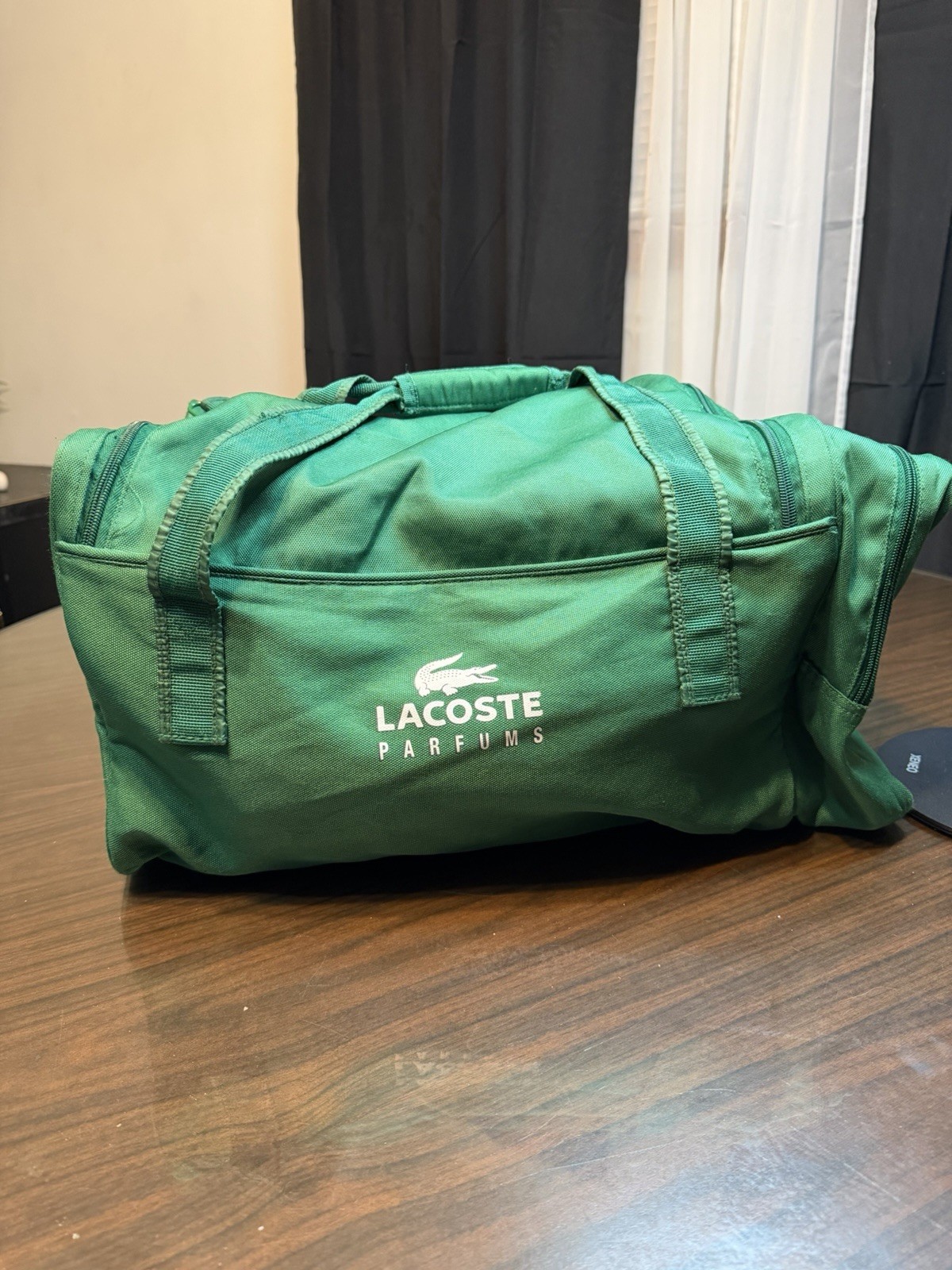 green Lacoste Parfums promotional duffle bag featuring brand’s crocodile logo.