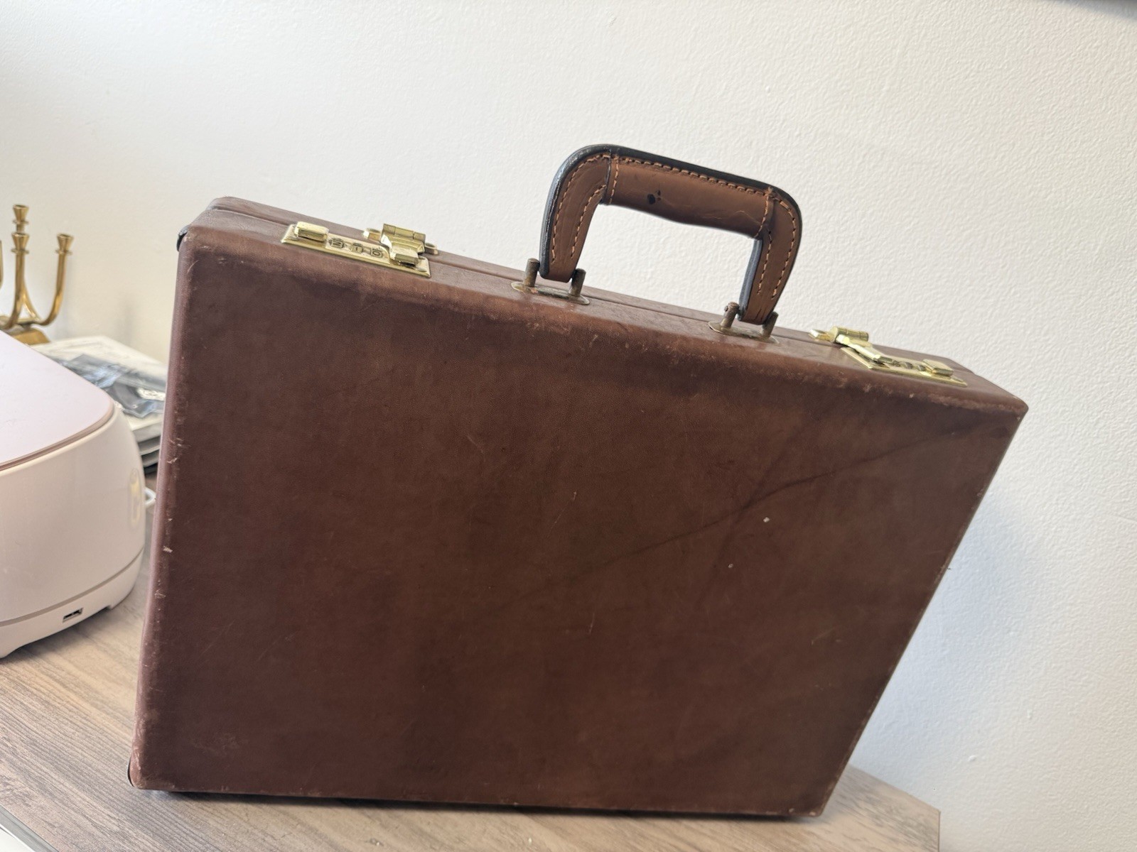 A vintage brown leather briefcase with combination lock and metal hardware.