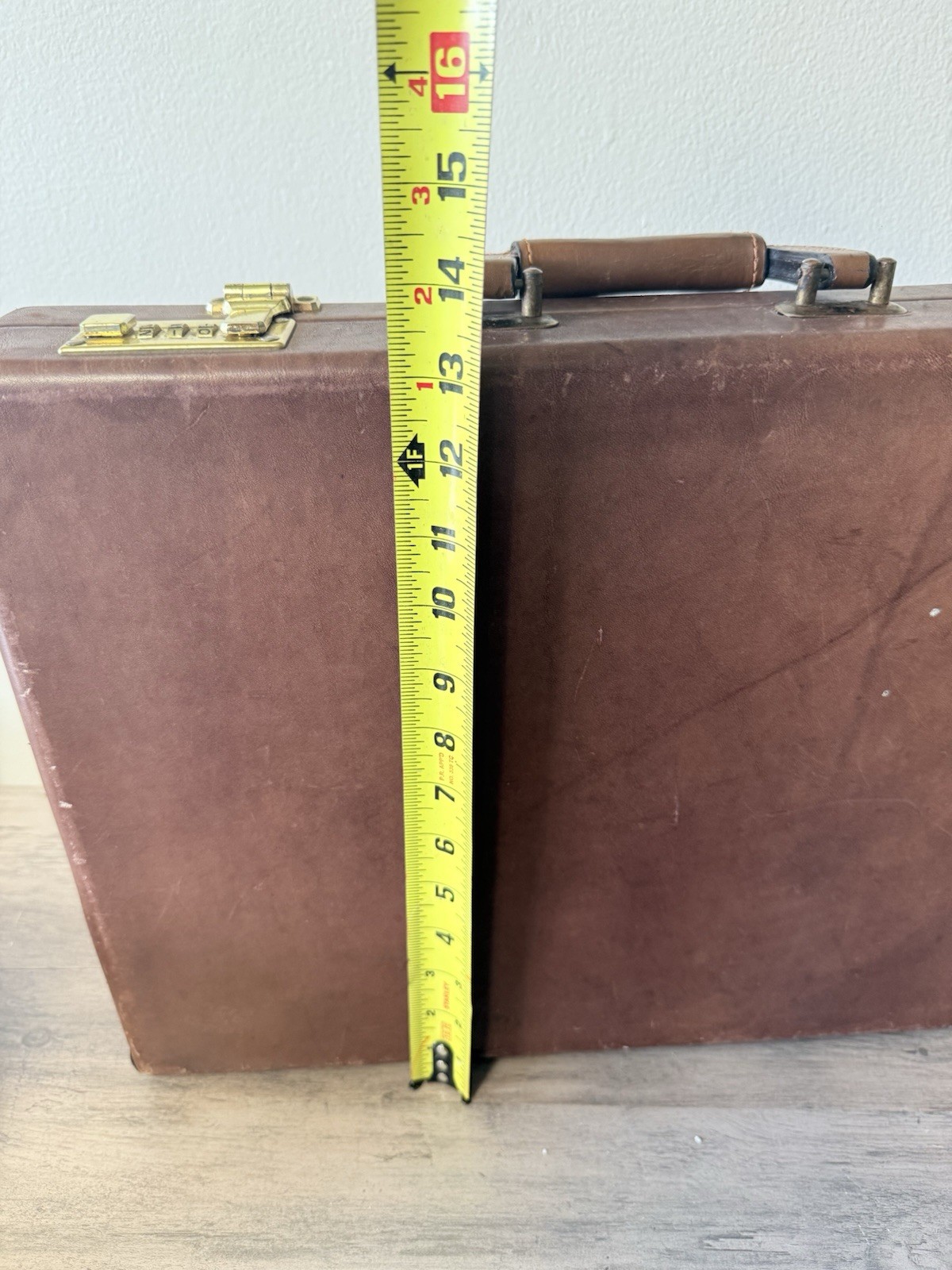 A vintage brown leather briefcase with combination lock and metal hardware.