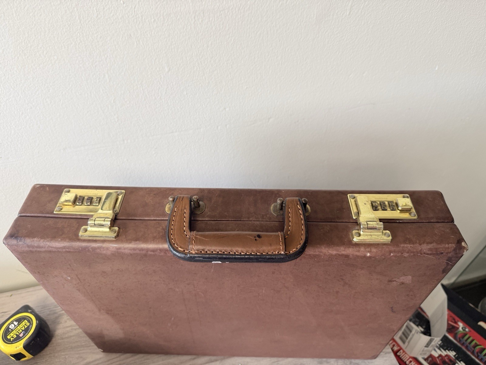 A vintage brown leather briefcase with combination lock and metal hardware.