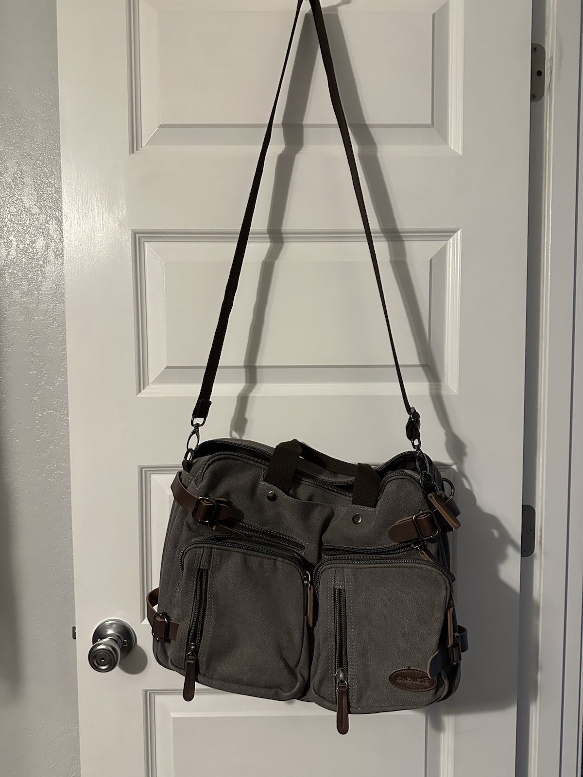 gray canvas messenger bag featuring a leather “SHENG1S” branded