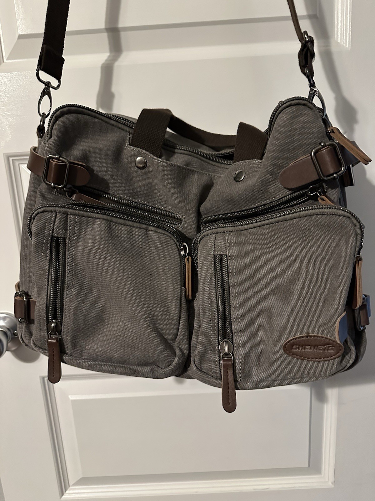 gray canvas messenger bag featuring a leather “SHENG1S” branded