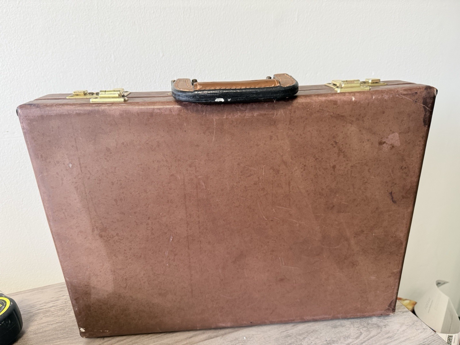 A vintage brown leather briefcase with combination lock and metal hardware.